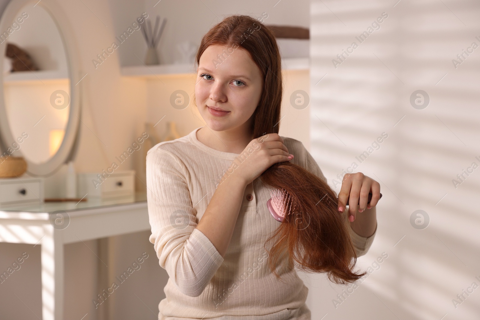 Photo of Beautiful teenage girl brushing her hair at home