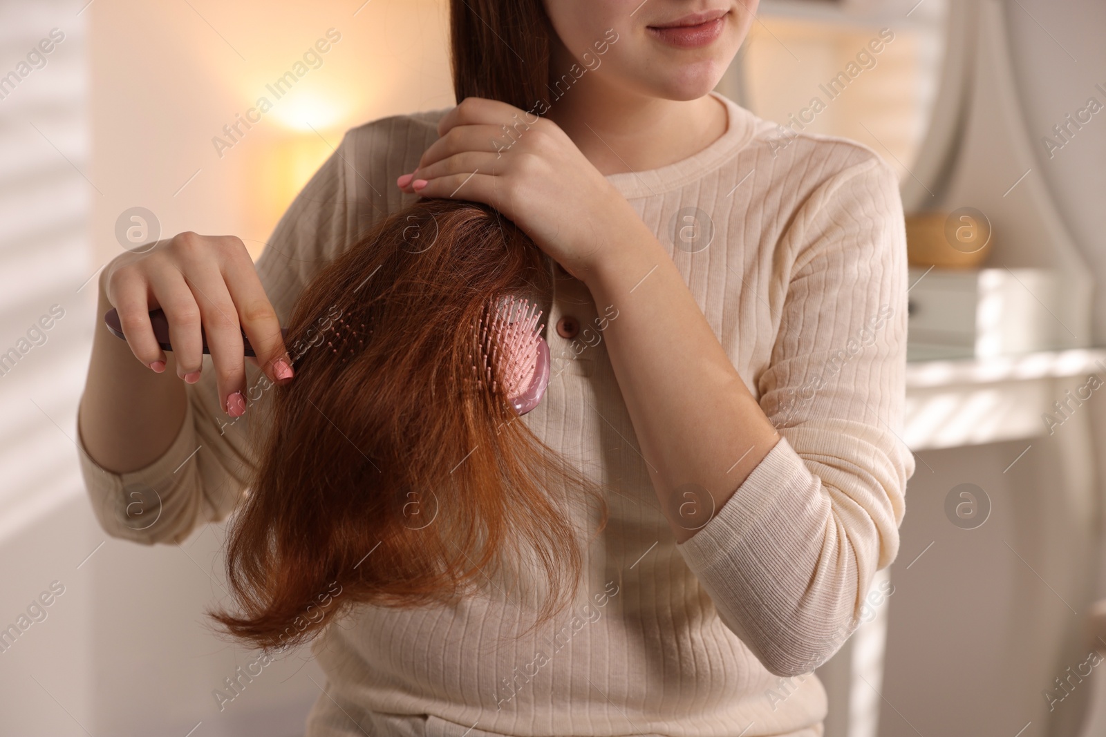 Photo of Teenage girl brushing her hair at home, closeup