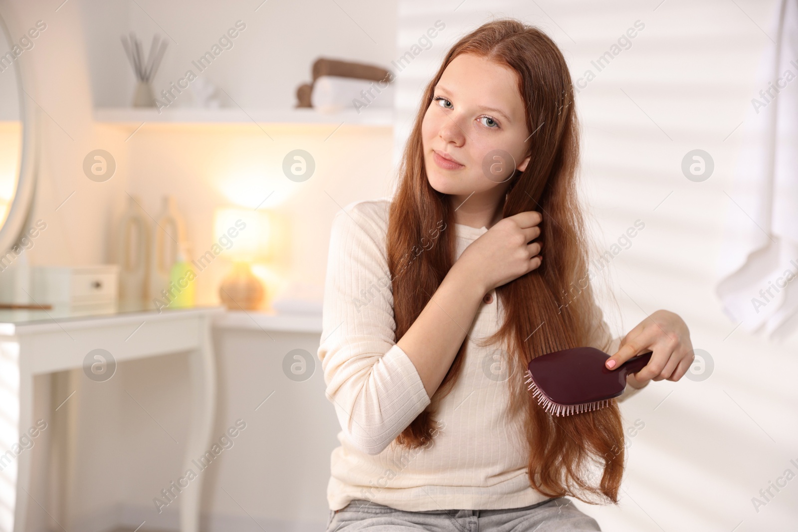 Photo of Beautiful teenage girl brushing her hair at home, space for text