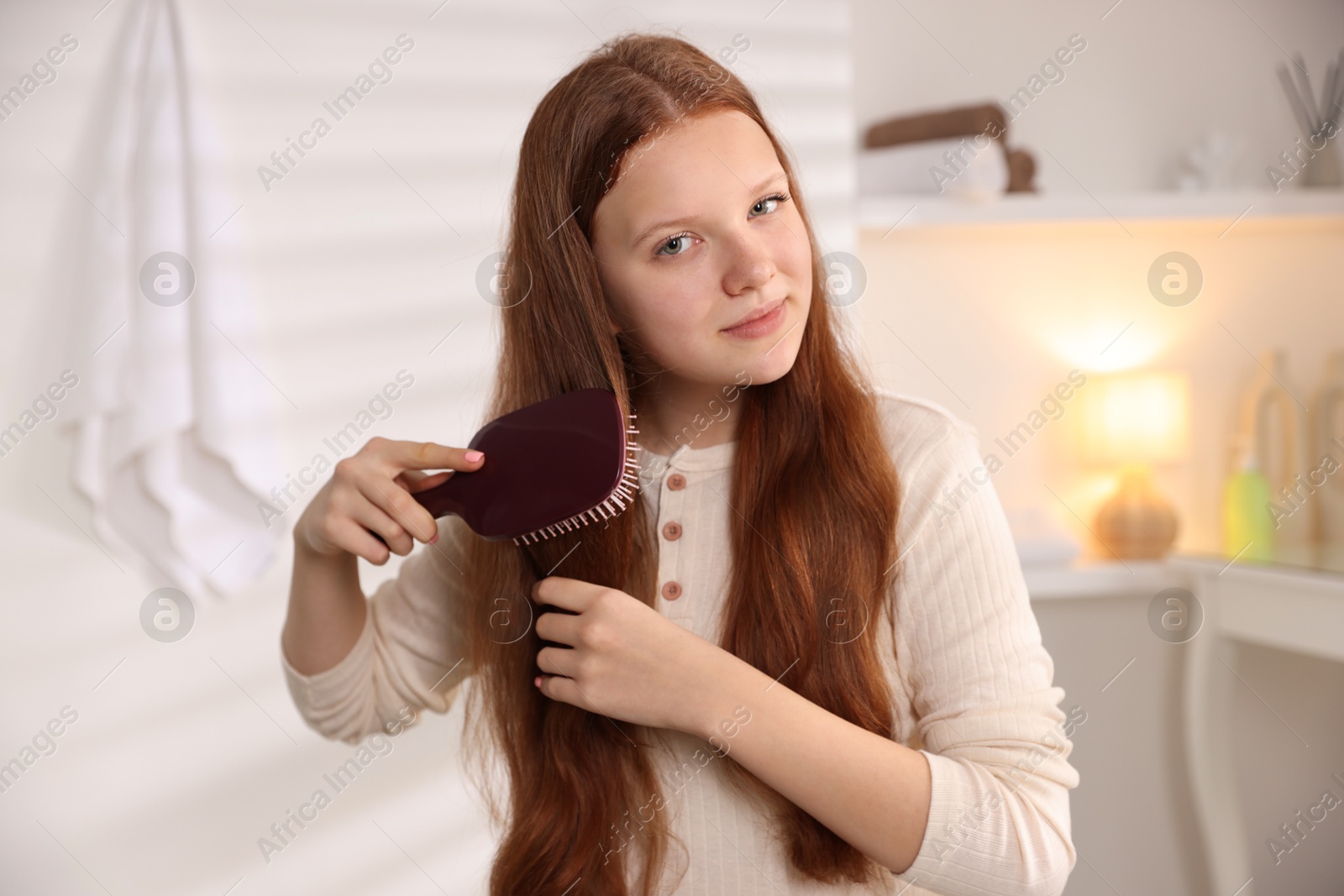 Photo of Beautiful teenage girl brushing her hair at home