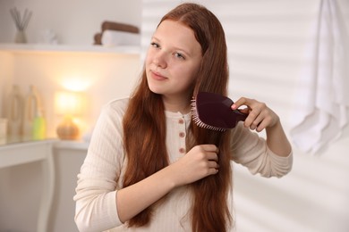 Photo of Beautiful teenage girl brushing her hair at home