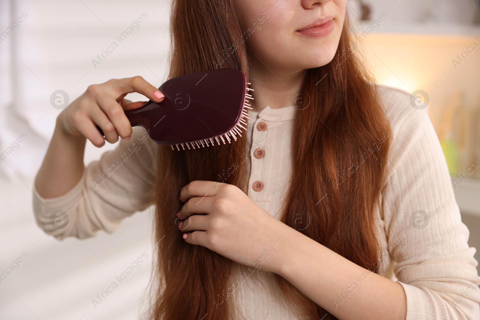 Photo of Teenage girl brushing her hair at home, closeup