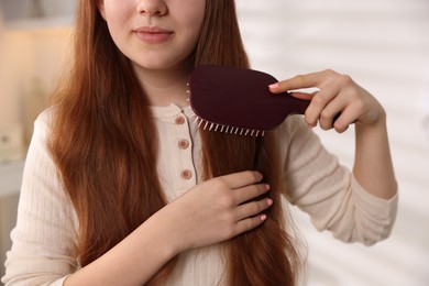 Photo of Teenage girl brushing her hair at home, closeup