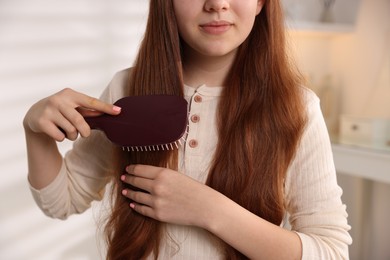 Photo of Teenage girl brushing her hair at home, closeup