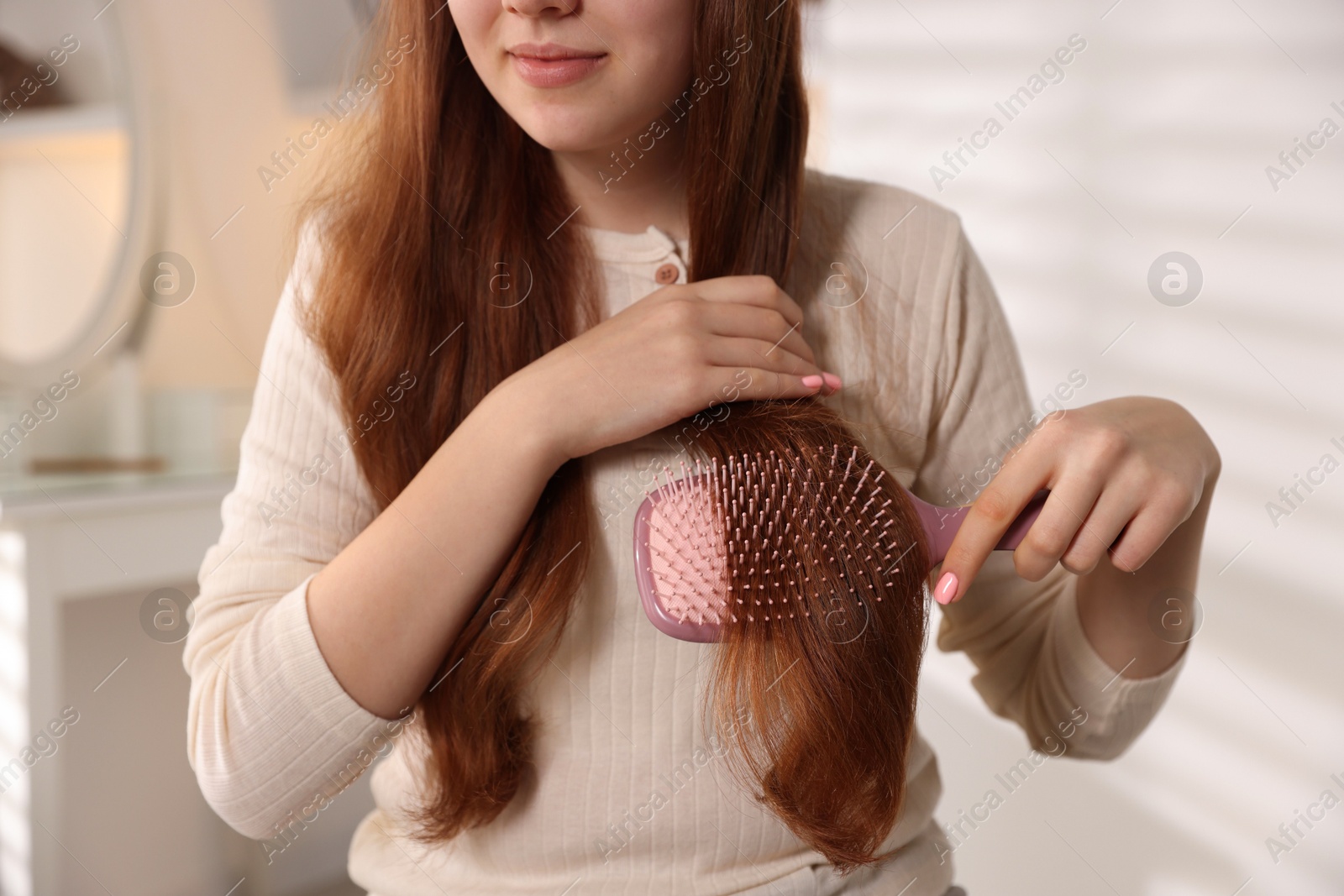 Photo of Teenage girl brushing her hair at home, closeup