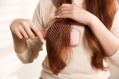 Photo of Teenage girl brushing her hair at home, closeup