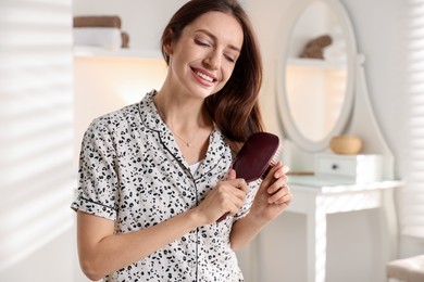 Photo of Smiling woman brushing her hair at home