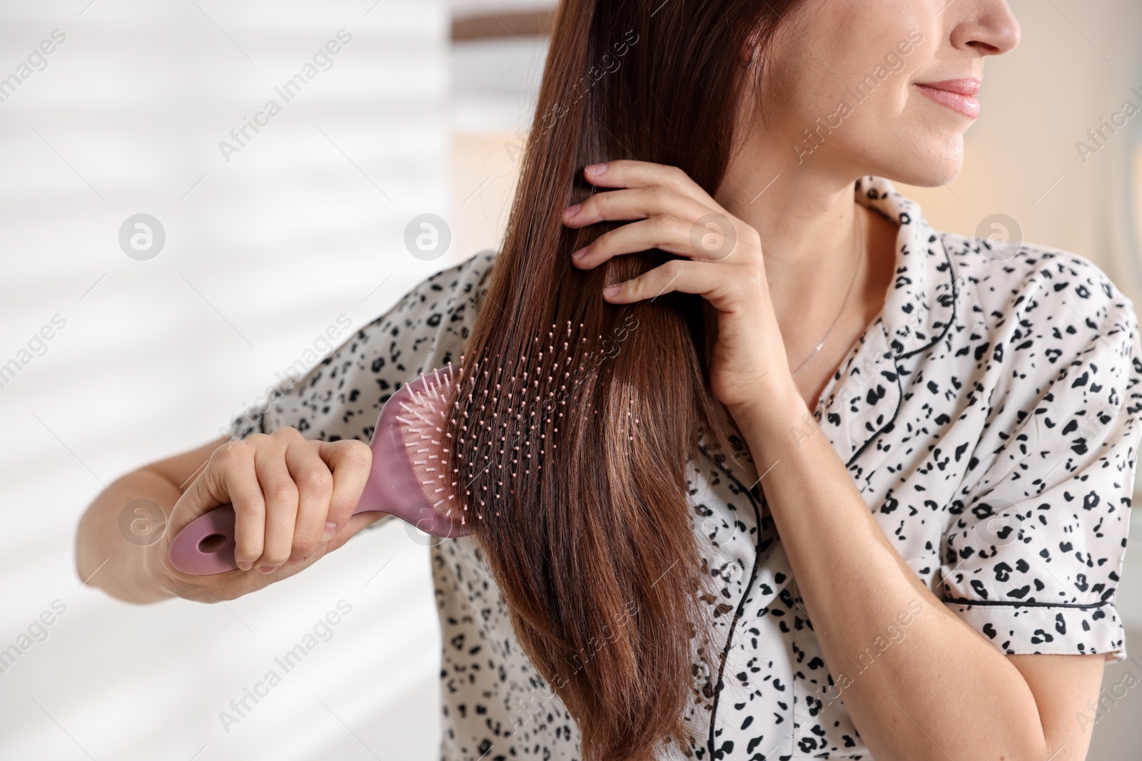 Photo of Woman brushing her hair at home, closeup