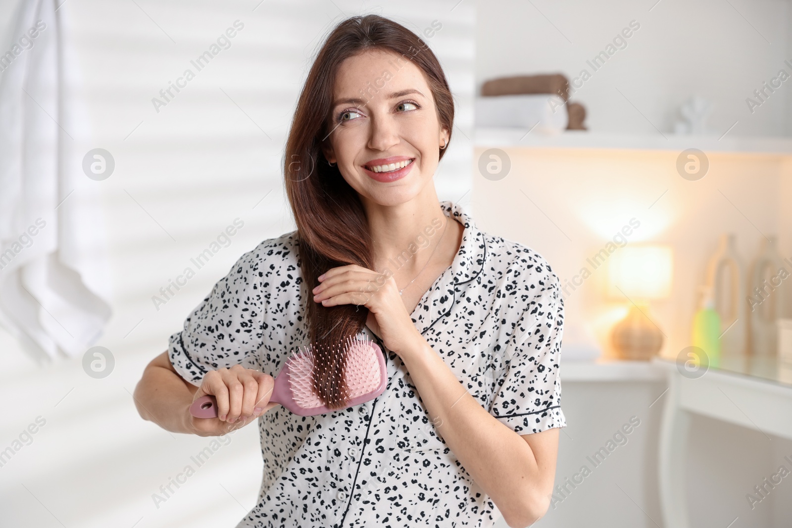 Photo of Smiling woman brushing her hair at home