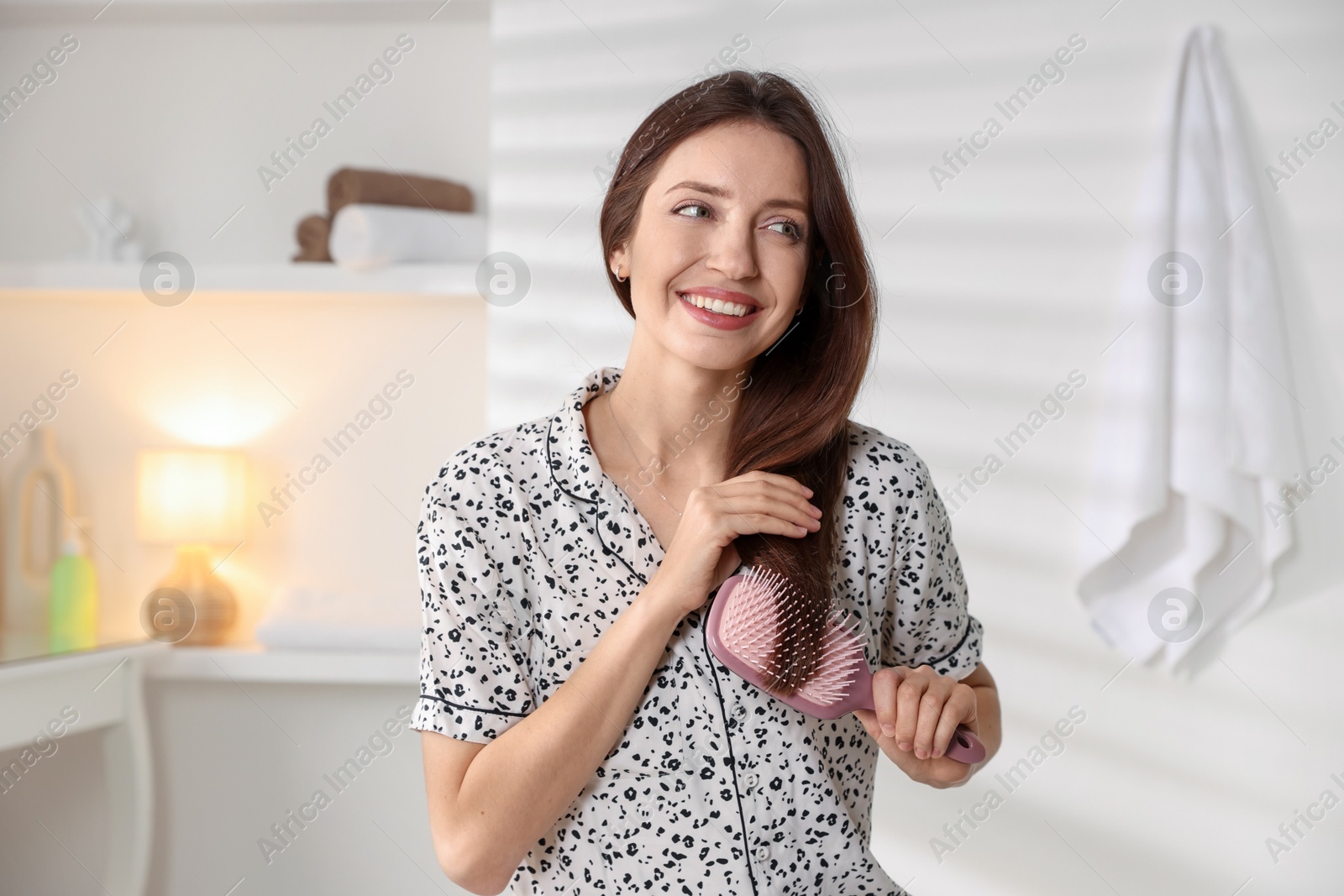 Photo of Smiling woman brushing her hair at home