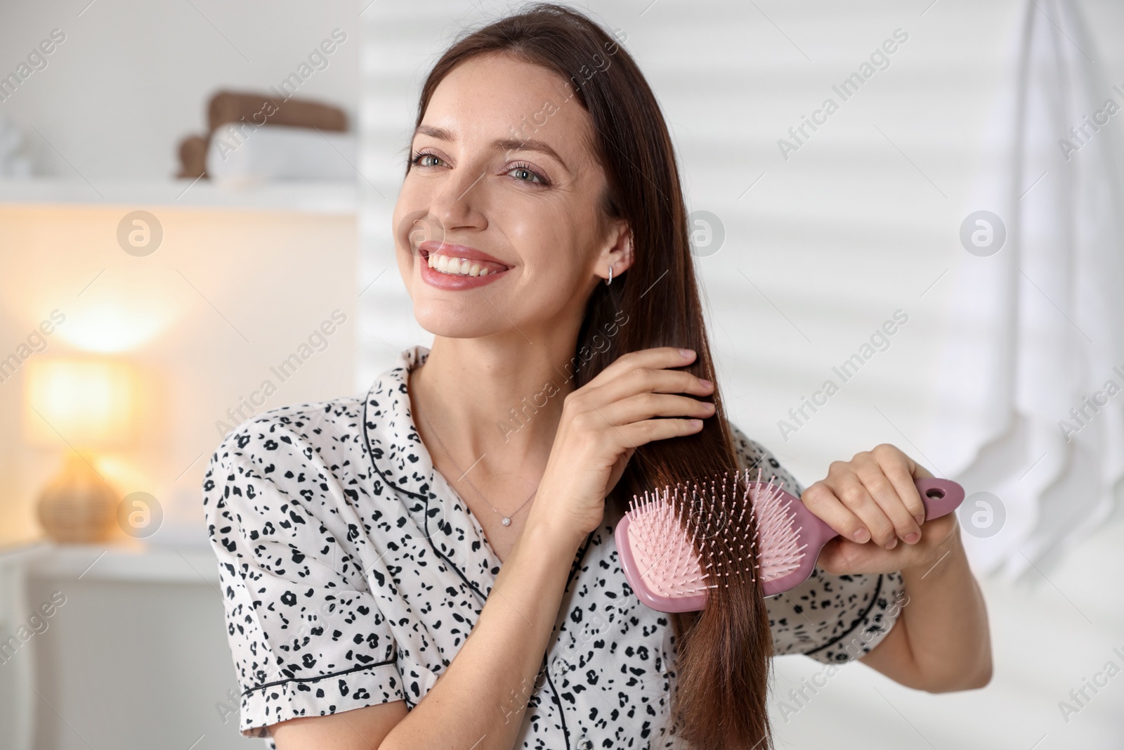 Photo of Smiling woman brushing her hair at home