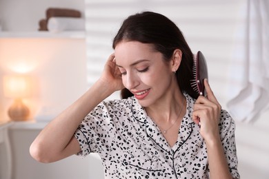 Photo of Smiling woman brushing her hair at home