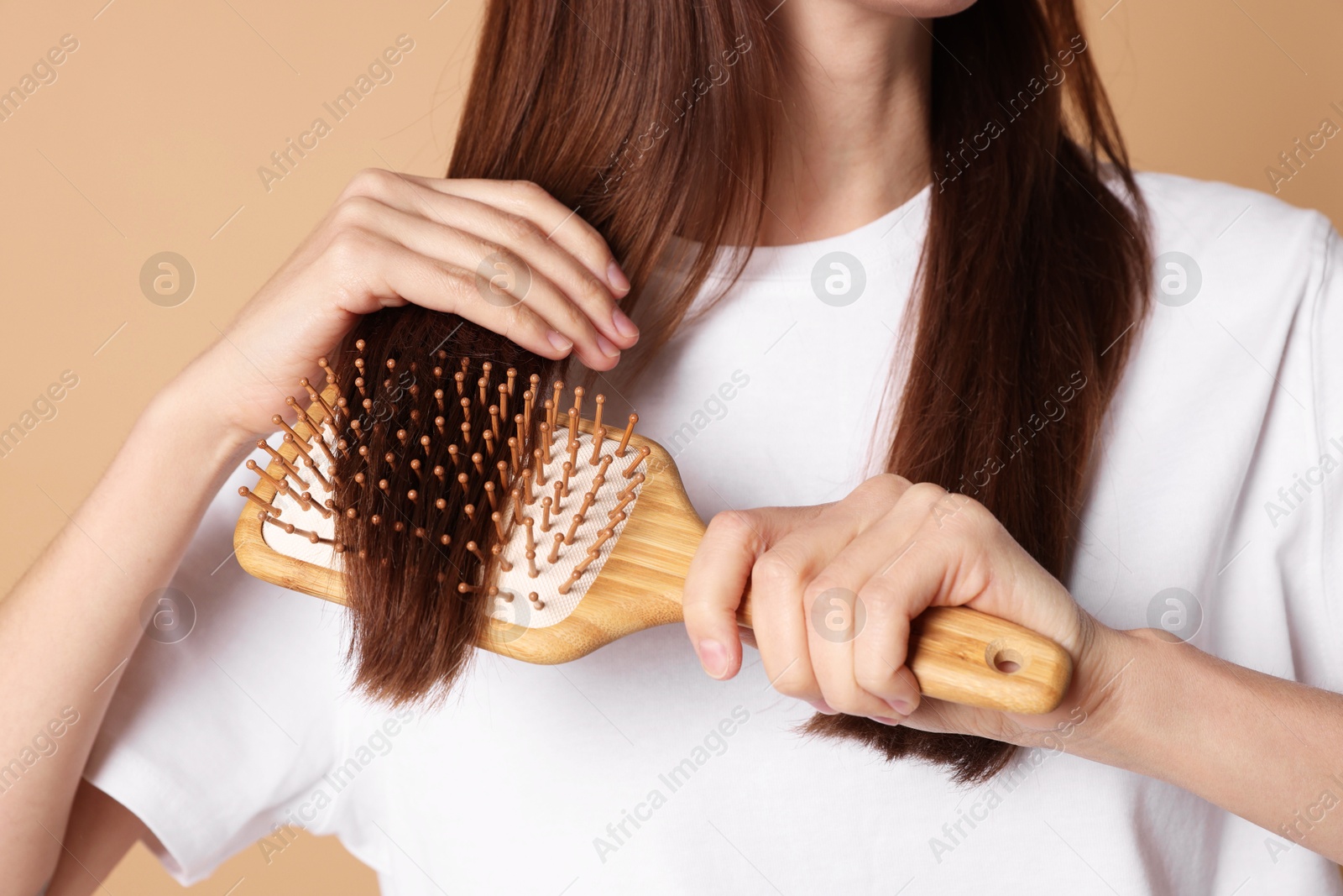 Photo of Woman brushing her hair on beige background, closeup