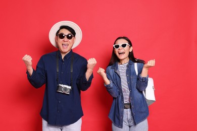 Photo of Couple of excited travellers on red background