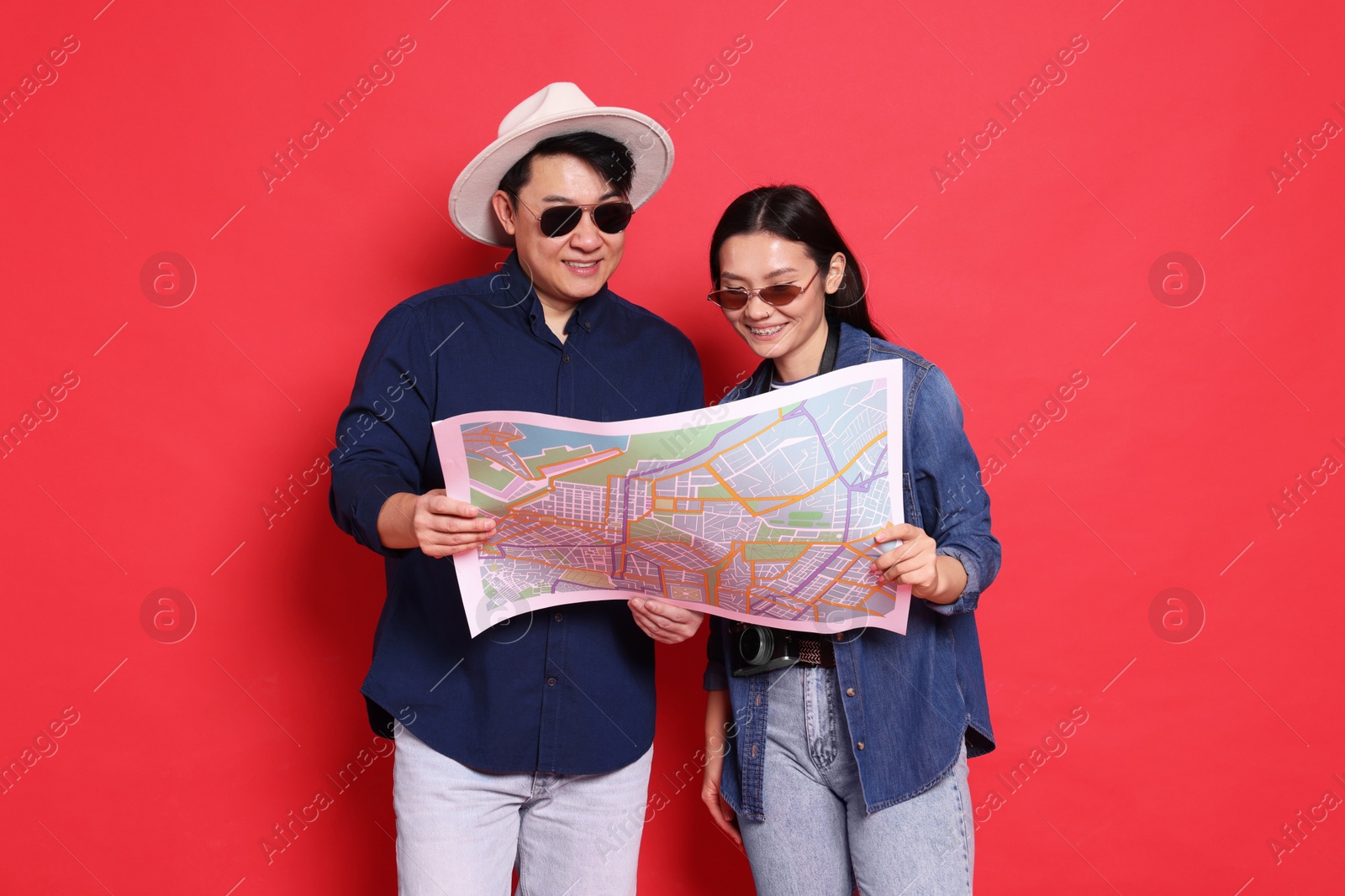 Photo of Happy travellers with map on red background