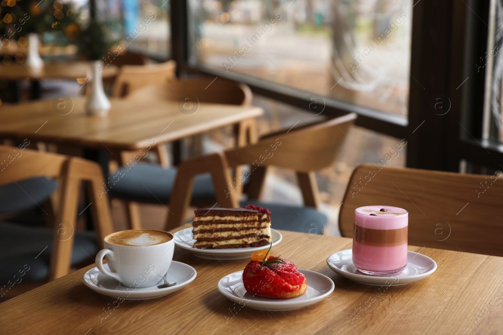 Photo of Aromatic coffee and delicious desserts served on wooden table in cafe