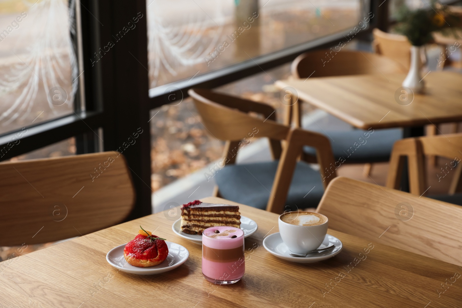 Photo of Aromatic coffee and delicious desserts served on wooden table in cafe