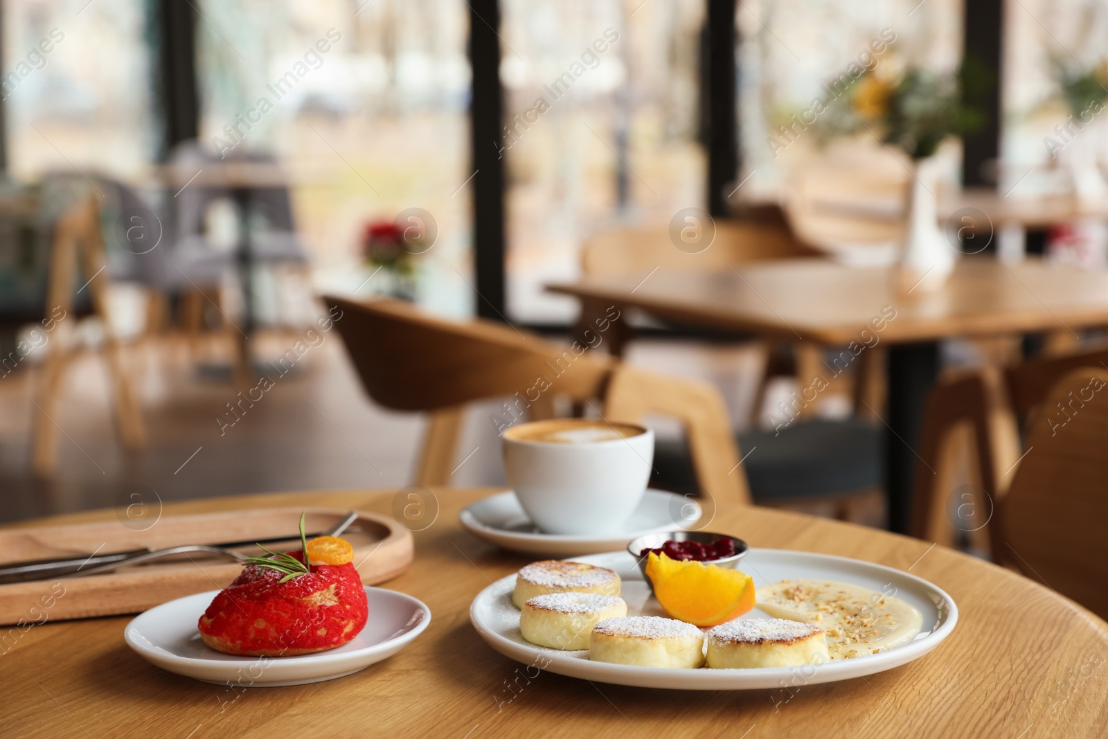 Photo of Delicious cottage cheese pancakes, dessert and coffee served on wooden table in cafe