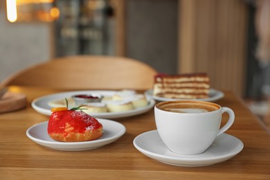 Photo of Aromatic coffee and delicious desserts served on wooden table in cafe