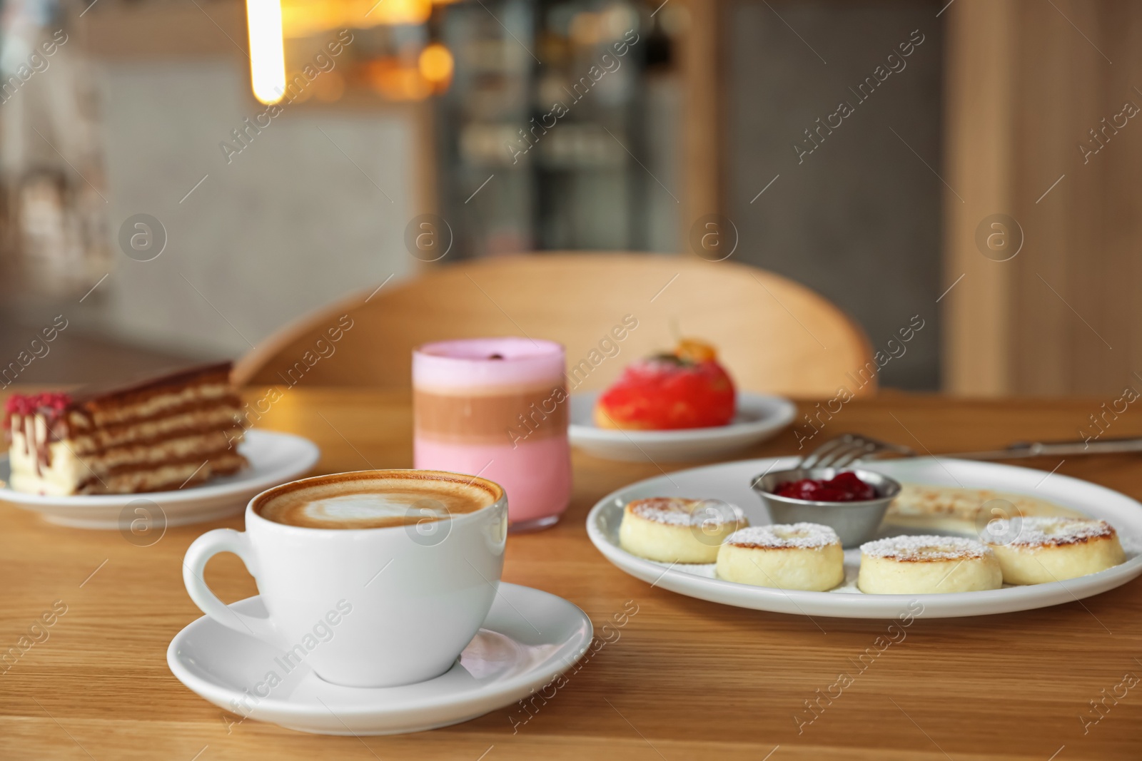 Photo of Delicious cottage cheese pancakes, desserts and aromatic coffee served on wooden table in cafe