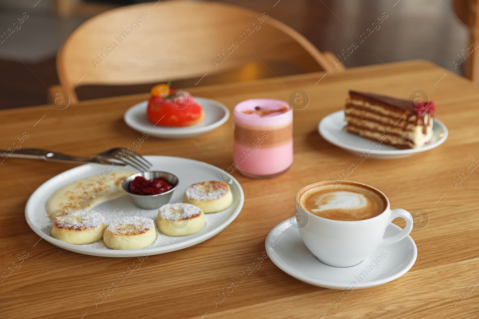 Photo of Delicious cottage cheese pancakes, desserts and aromatic coffee served on wooden table in cafe