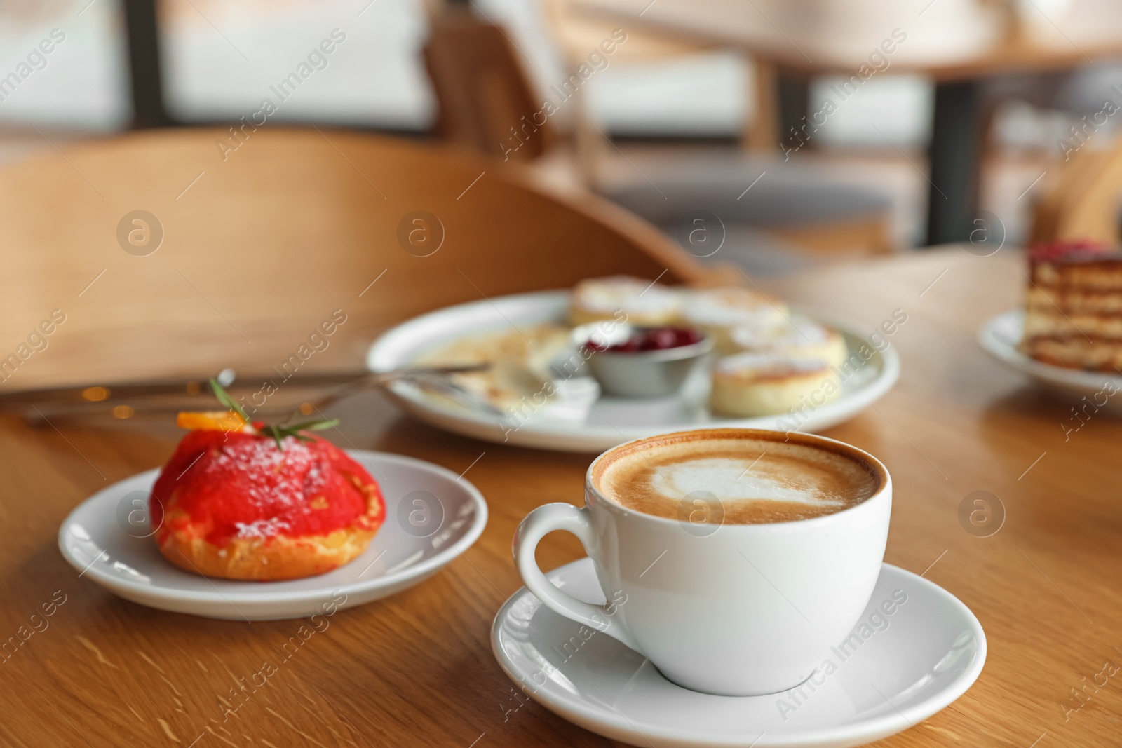 Photo of Aromatic coffee and delicious desserts served on wooden table in cafe