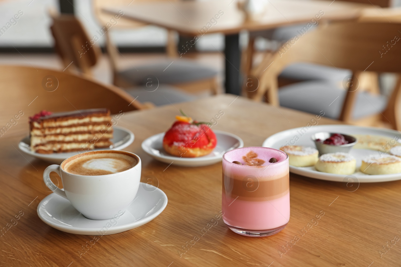 Photo of Delicious cottage cheese pancakes, desserts and aromatic coffee served on wooden table in cafe