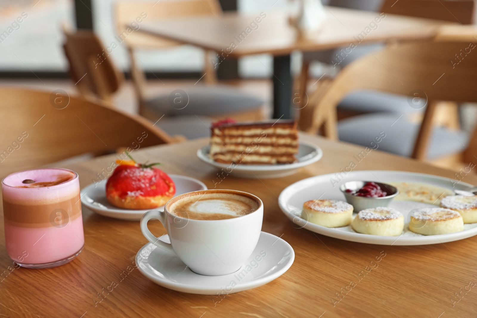 Photo of Delicious cottage cheese pancakes, desserts and aromatic coffee served on wooden table in cafe