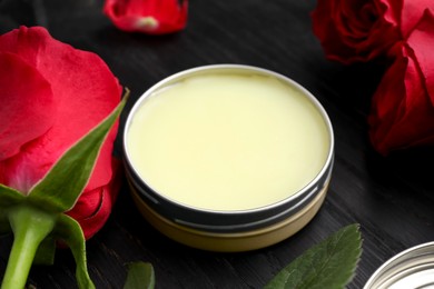 Photo of Natural solid perfume and roses on black wooden table, closeup