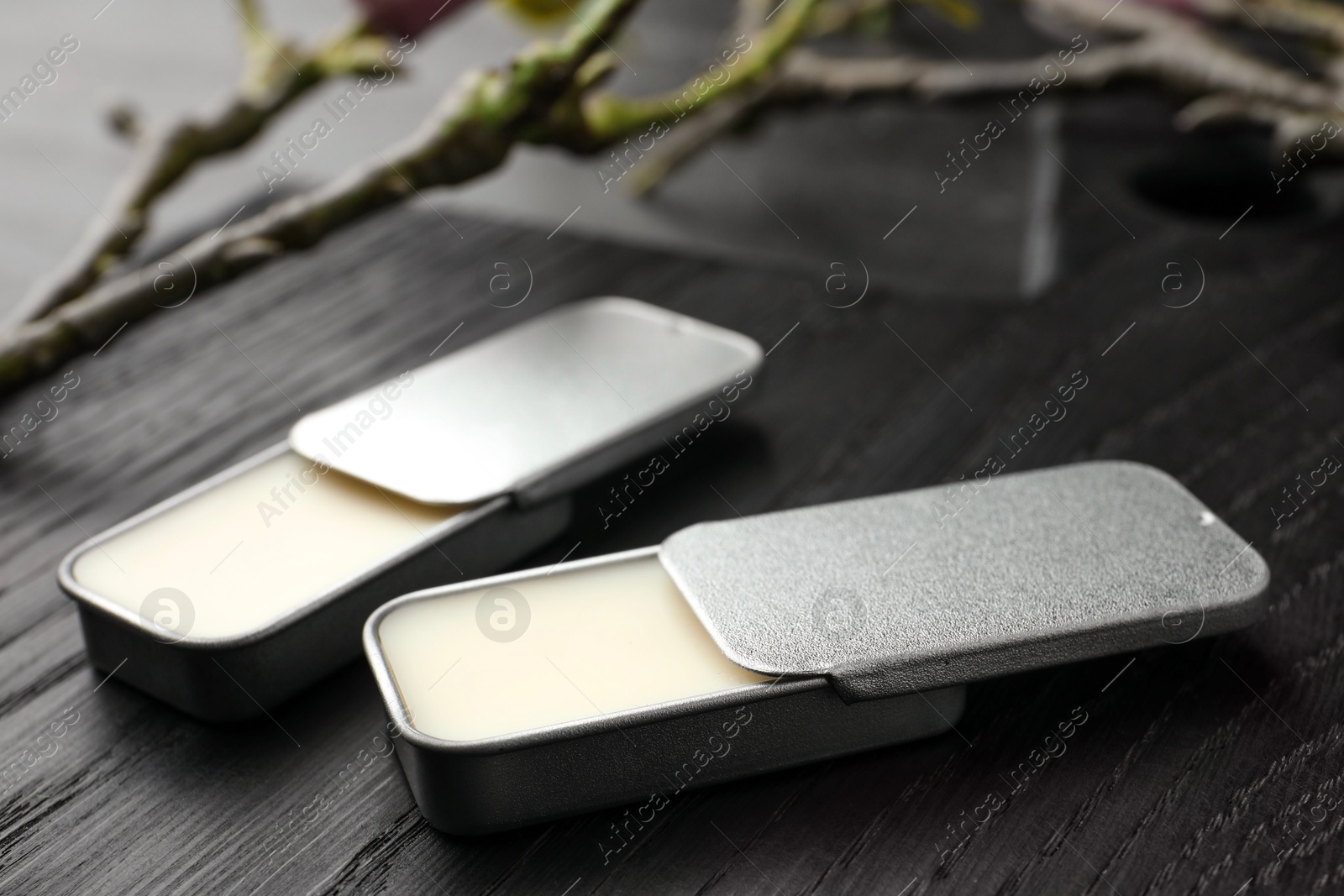 Photo of Natural solid perfume and branch on black wooden table, closeup