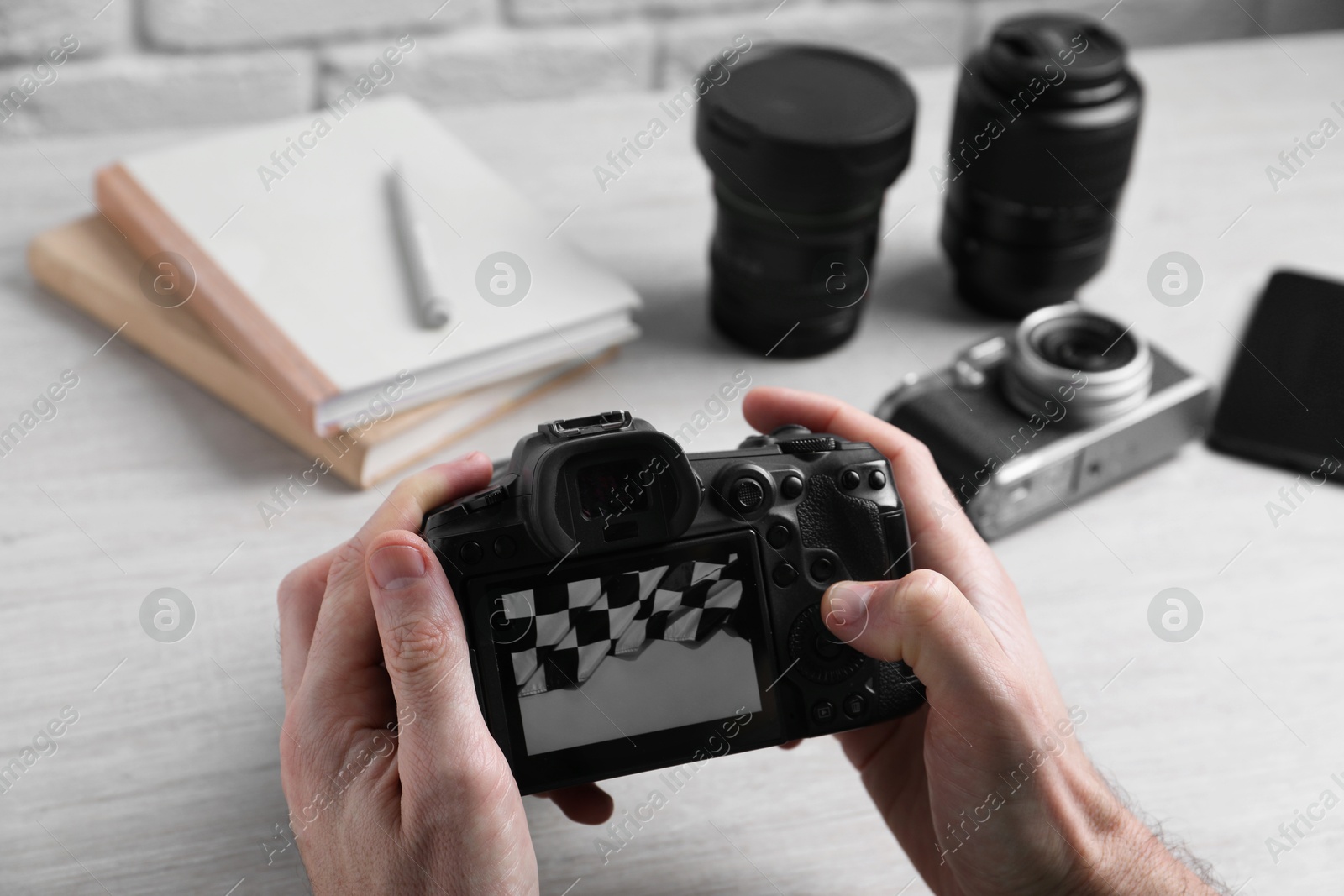 Photo of Photographer with professional camera at wooden table, closeup