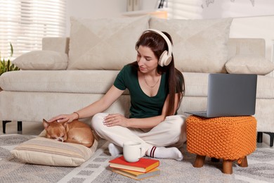 Photo of Young woman working on laptop while her cute dog sleeping beside at home