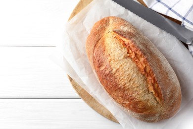 Photo of Loaf of delicious bread on white wooden table, top view. Space for text