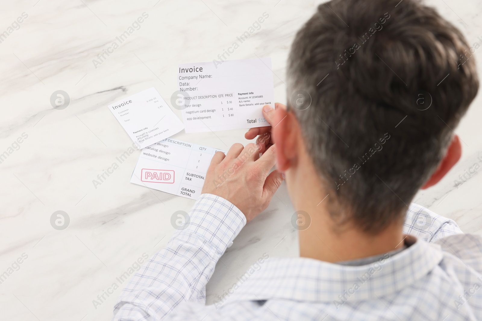 Photo of Paying bills. Man with different invoices at white marble table, above view