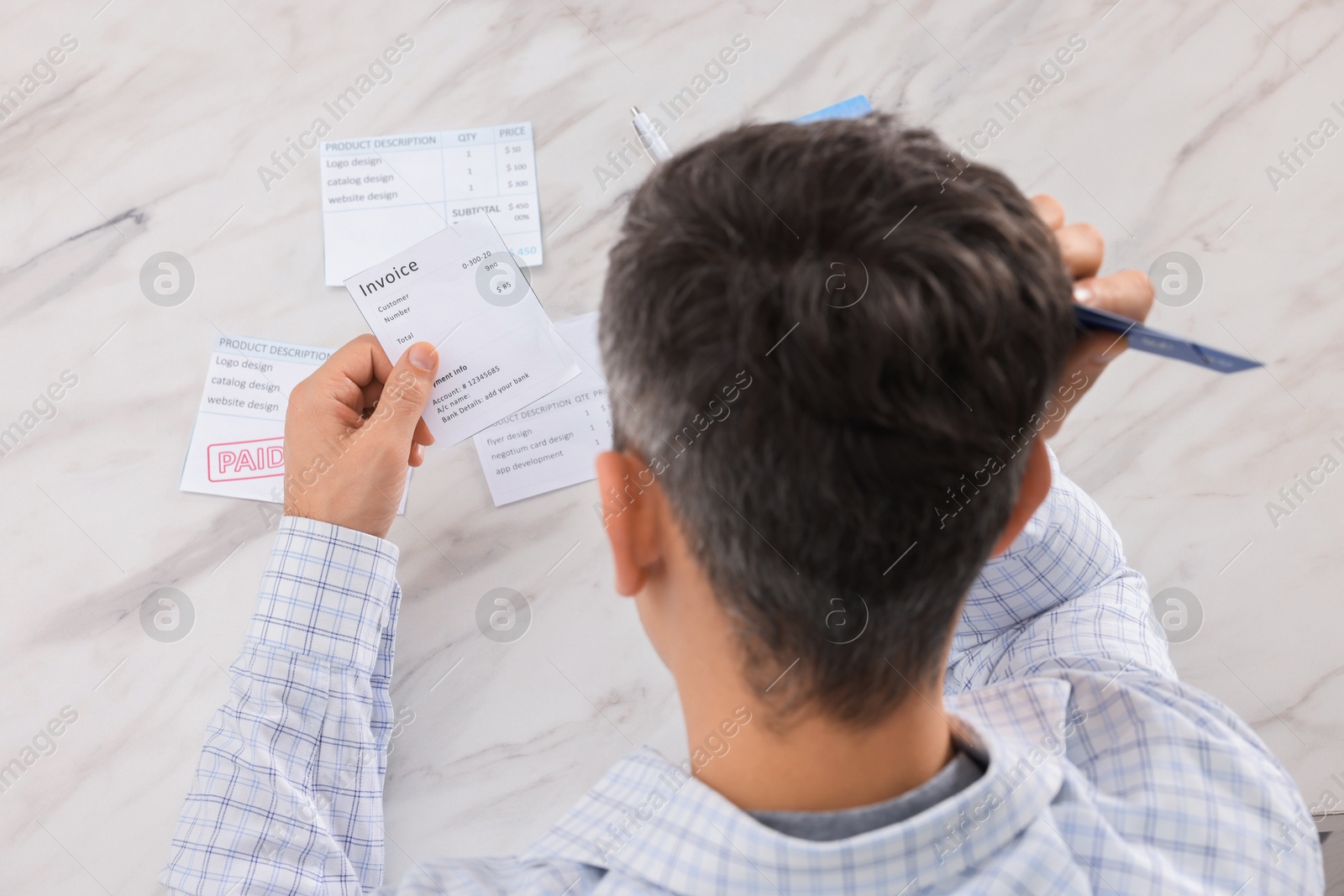 Photo of Paying bills. Man with different invoices at white marble table, above view