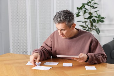 Photo of Paying bills. Man with different invoices at wooden table