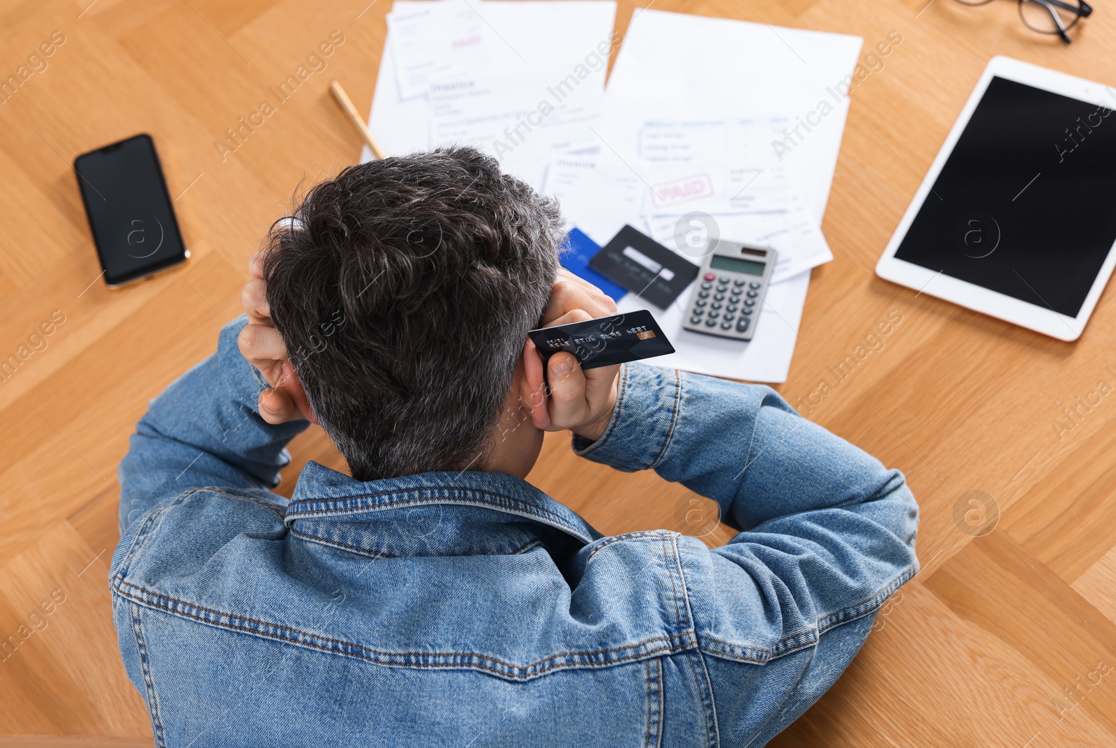 Photo of Paying bills. Man with reviewing invoices at wooden table, above view