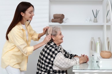 Photo of Woman brushing senior lady with brush indoors