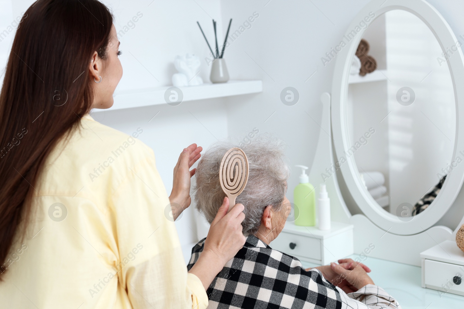 Photo of Woman brushing senior lady with brush indoors