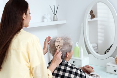 Photo of Woman brushing senior lady with brush indoors