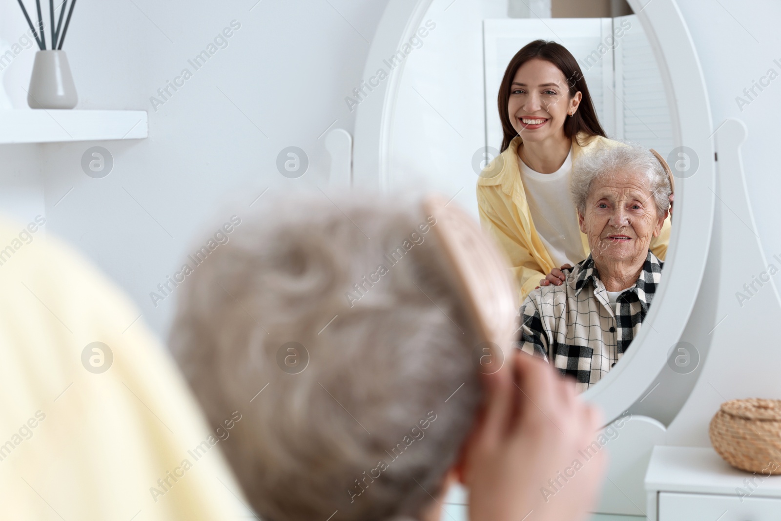 Photo of Woman brushing senior lady with brush indoors