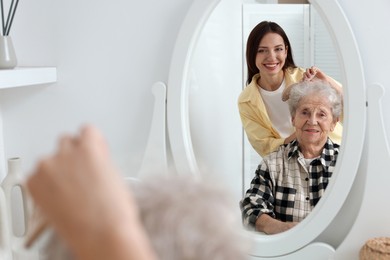 Photo of Woman brushing senior lady with brush indoors