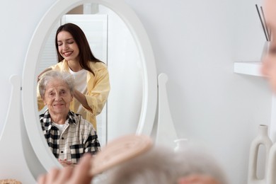 Photo of Woman brushing senior lady with brush indoors