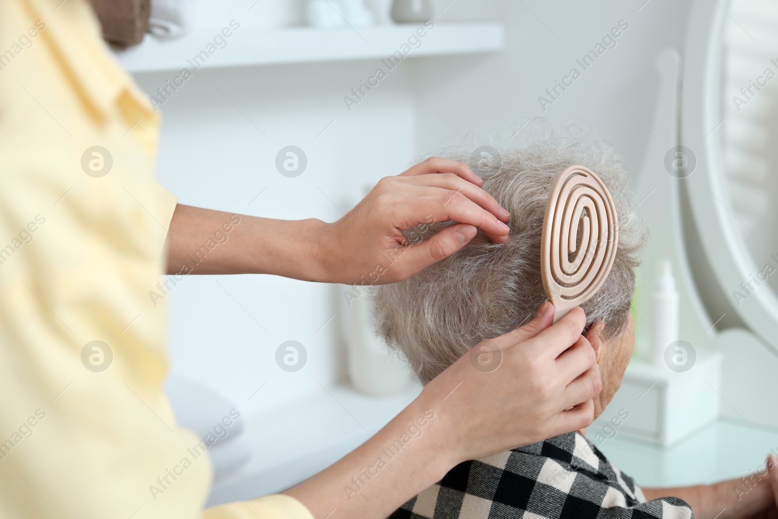 Photo of Woman brushing senior lady with brush indoors, closeup