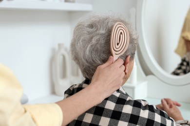 Photo of Woman brushing senior lady with brush indoors, closeup