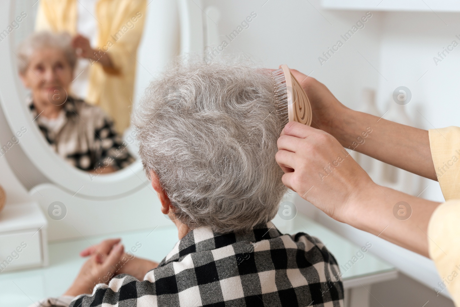 Photo of Woman brushing senior lady with brush indoors, closeup