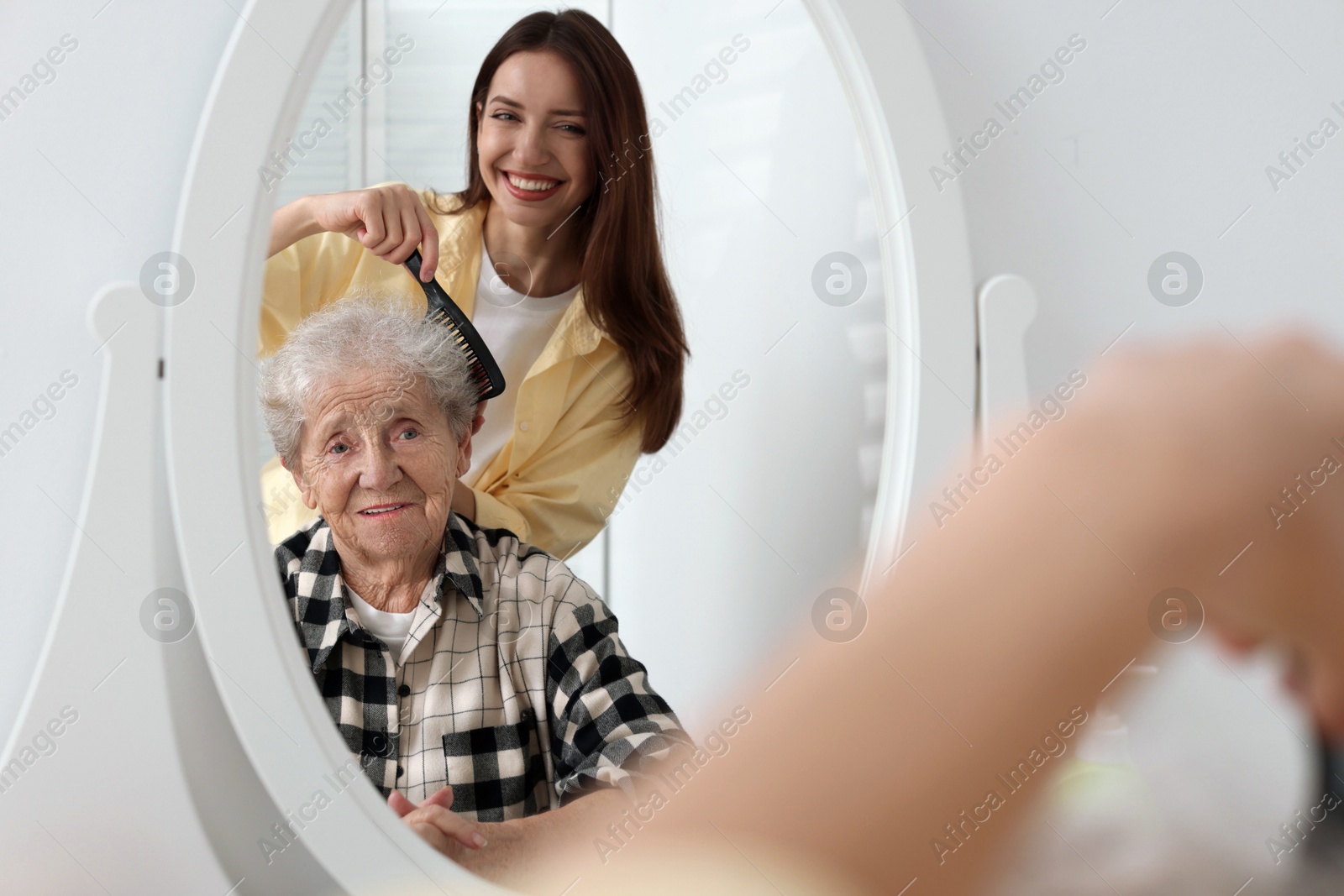 Photo of Woman brushing senior lady with comb indoors