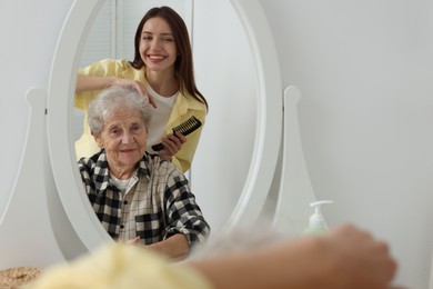 Photo of Woman brushing senior lady with comb indoors