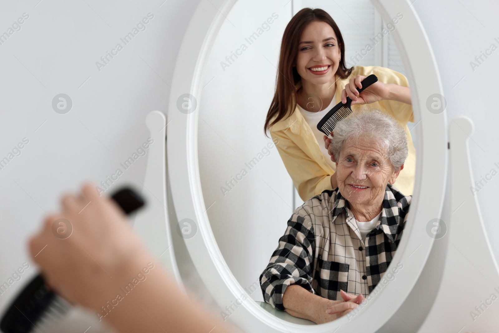 Photo of Woman brushing senior lady with comb indoors