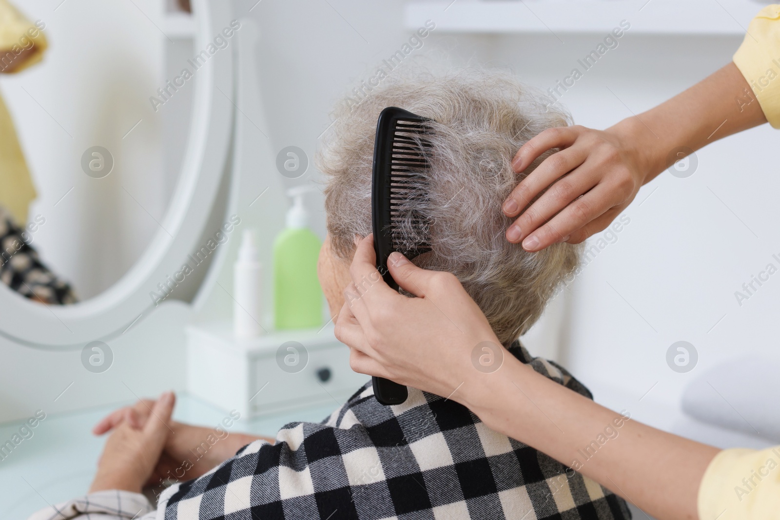 Photo of Woman brushing senior lady with comb indoors, closeup